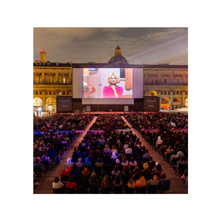 Foto di una proiezione in piazza maggiore di un film con il pubblico che guarda
