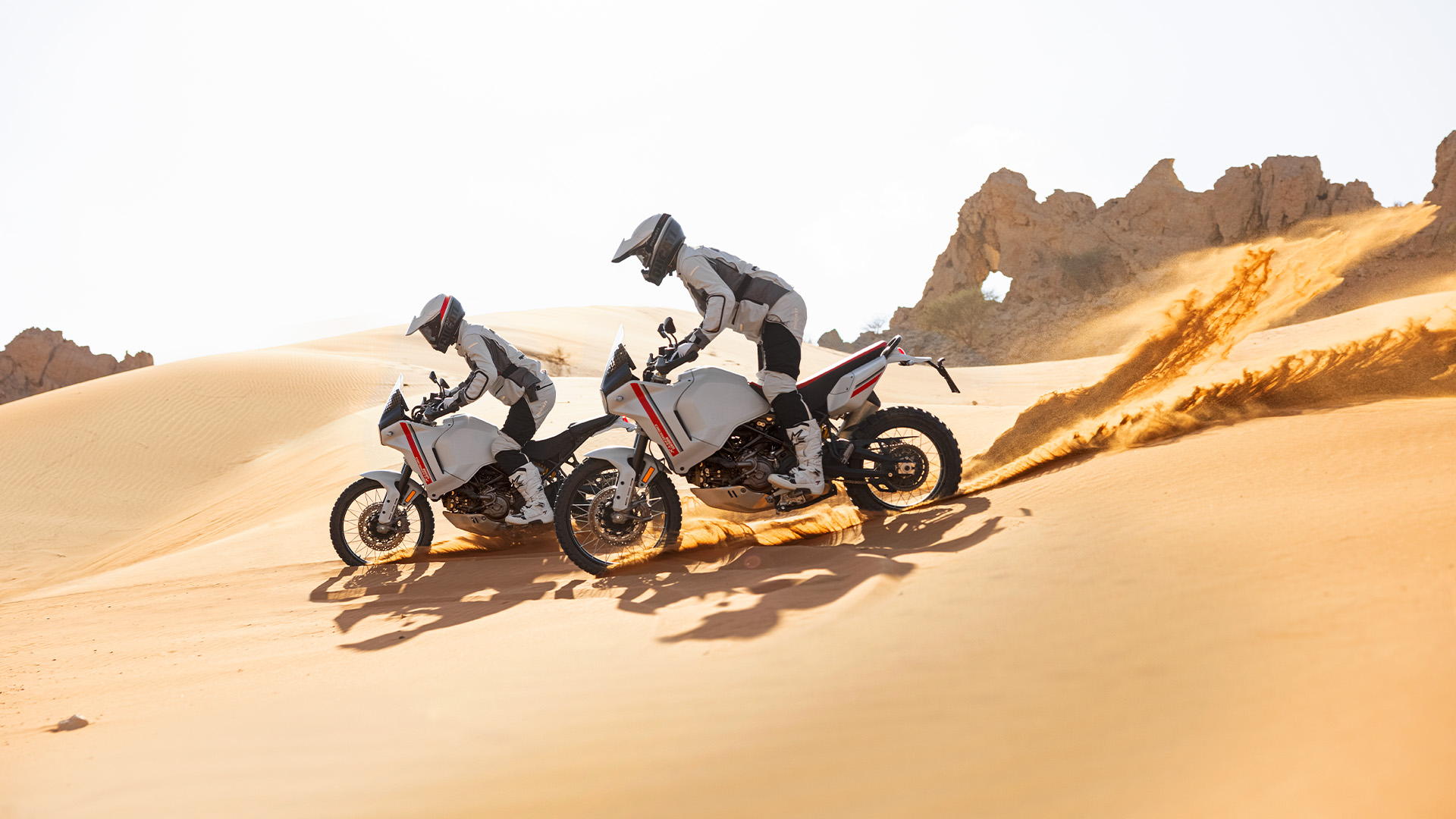 Due ducati desertX che percorrono un avvallamento tra le dune