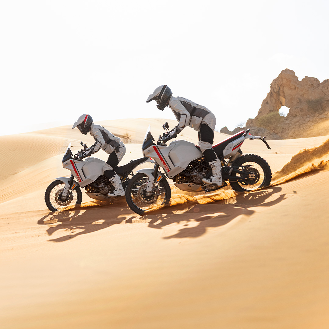 Due ducati desertX che percorrono un avvallamento tra le dune
