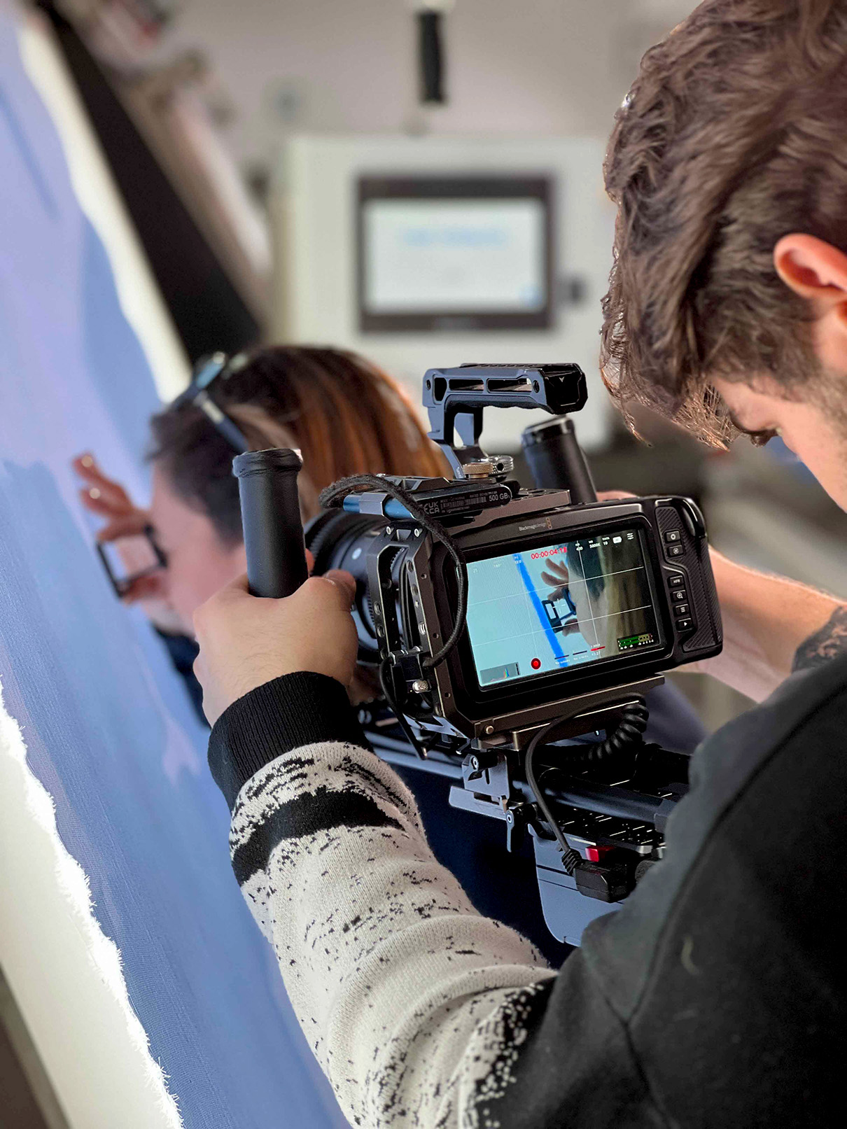 video maker che riprende un'operatrice che ispezione una tela di tessuto azzurro