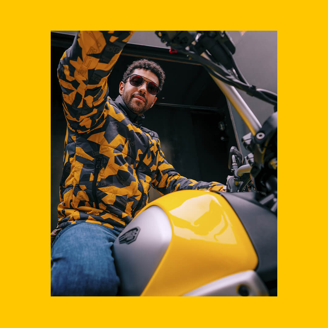scatto dal basso di un modello in sella ad una ducati scrambler gialla