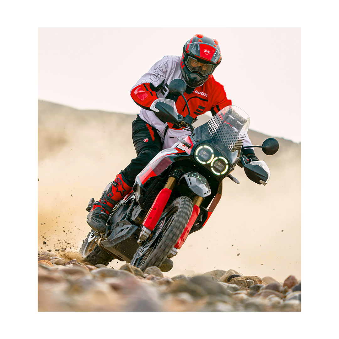 Una ducati desertX che guidata da un collaudatore percorre un tratto di strada roccioso